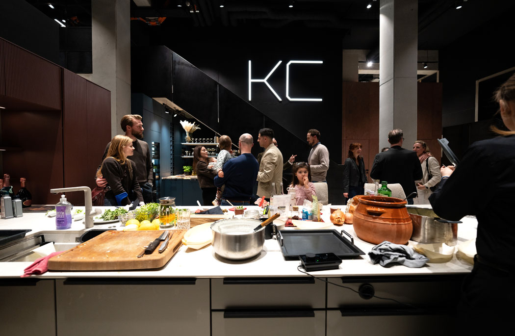 Eine lebhafte Kochveranstaltung mit Menschen, die in einer modernen Küche interagieren und frische Zutaten verwenden.